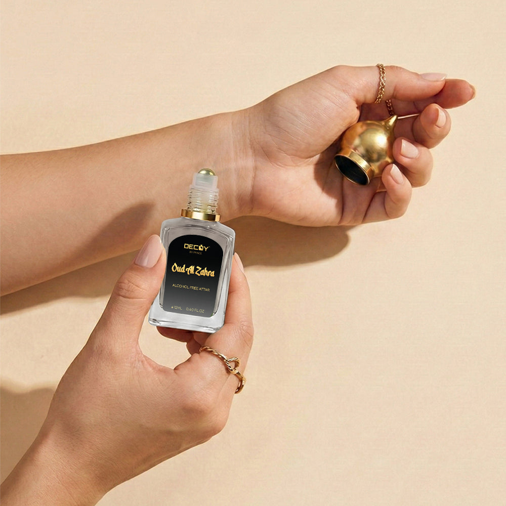 Hand holding a small bottle of Deoproce Oud Al zahra attar against a beige background