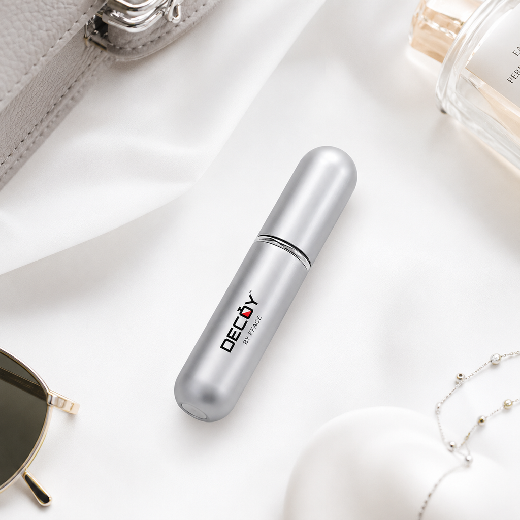 Silver cylindrical container with 'Decoy' branding on a white surface with sunglasses and a perfume bottle.