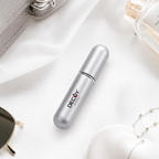 Silver cylindrical container with 'Decoy' branding on a white surface with sunglasses and a perfume bottle.