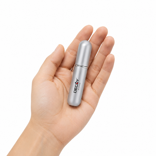 Silver cylindrical product with 'DECAY' branding held in a hand against a white background
