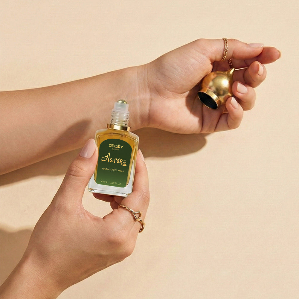 Hand holding a decoy luxury asrar attar oil bottle against a beige background