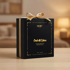Black perfume box with gold ribbon and text on a blurred background