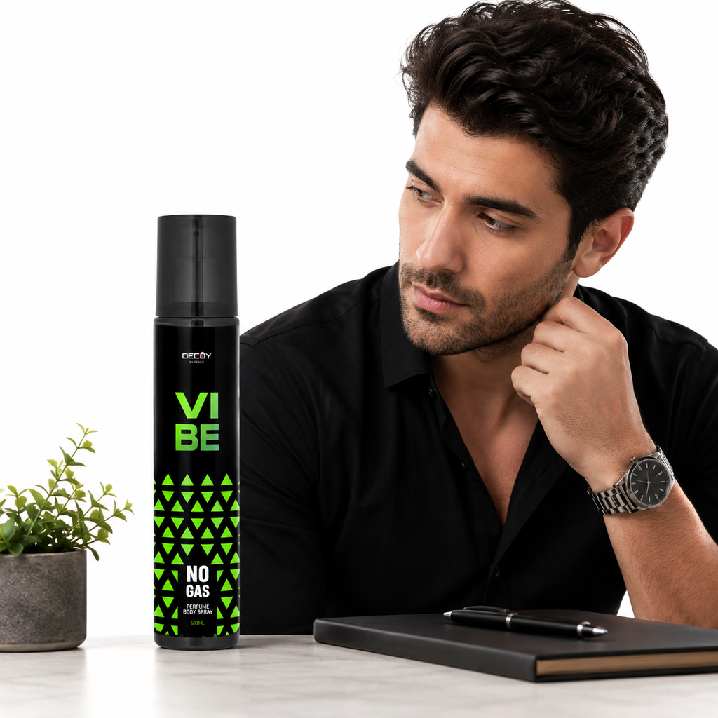 Man sitting at a desk with a bottle of 'Vibe' deodorant next to him