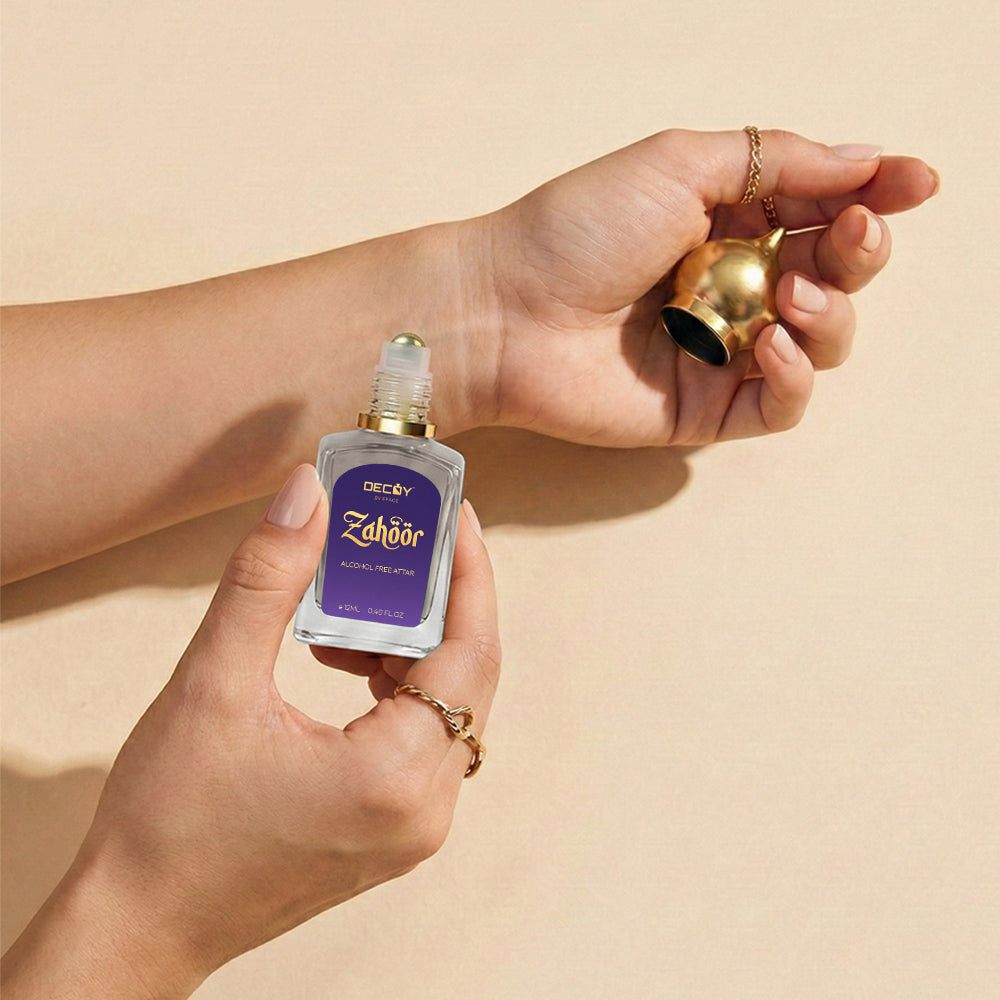 Hand holding a bottle of 'Zahoor' aftershave with a gold bell on a beige background